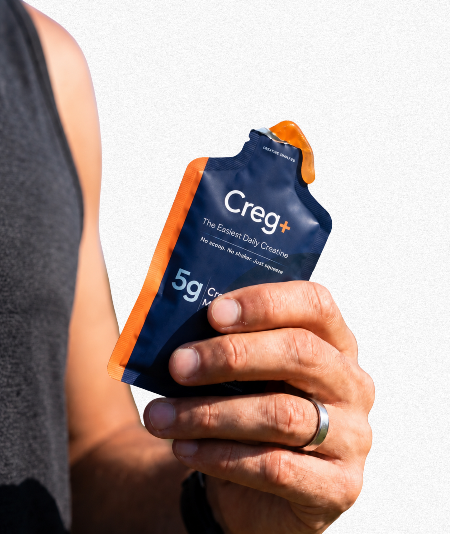 Hand holding a Creg+ product package against a gray background