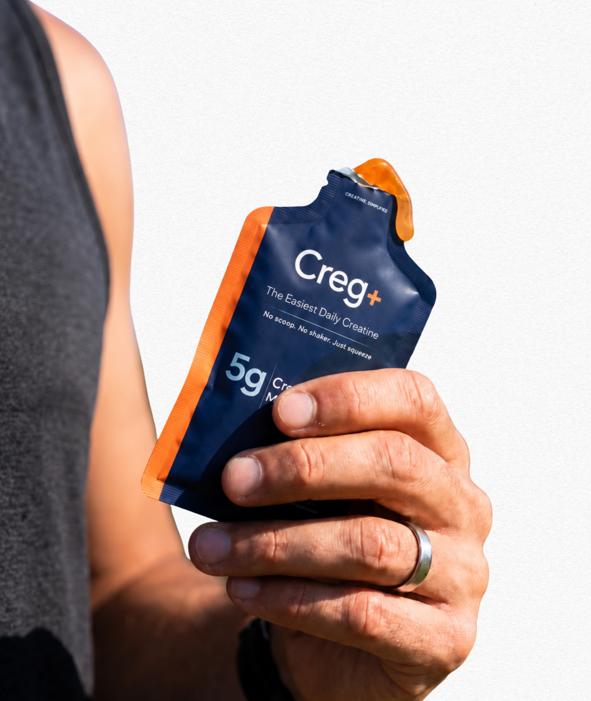 Hand holding a Creg+ product package against a gray background
